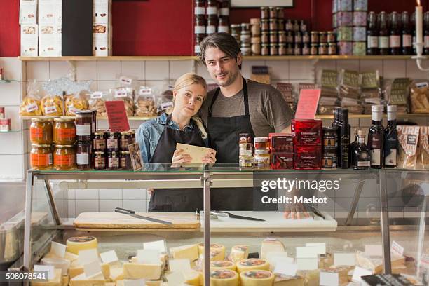 portrait of male and female worker standing at display cabinet in supermarket - cheesy salesman stockfoto's en -beelden