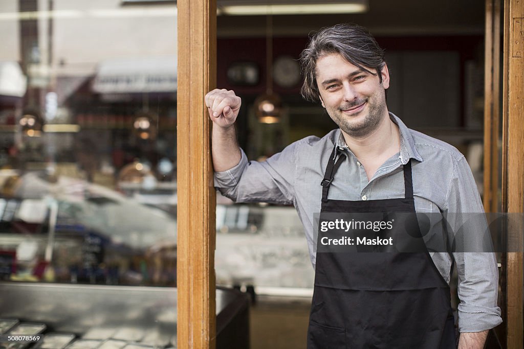 Portrait of confident salesman standing at supermarket entrance