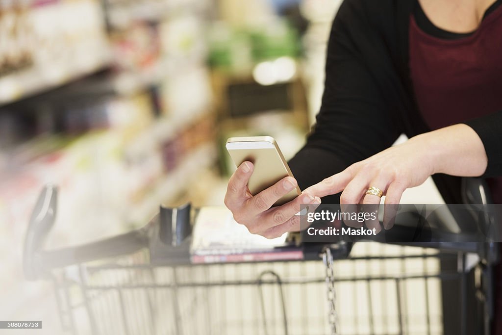 Midsection of woman checking shopping list in supermarket