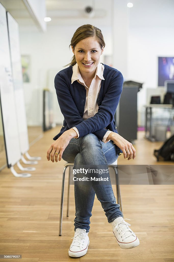 Full length portrait of confident businesswoman sitting on chair in office