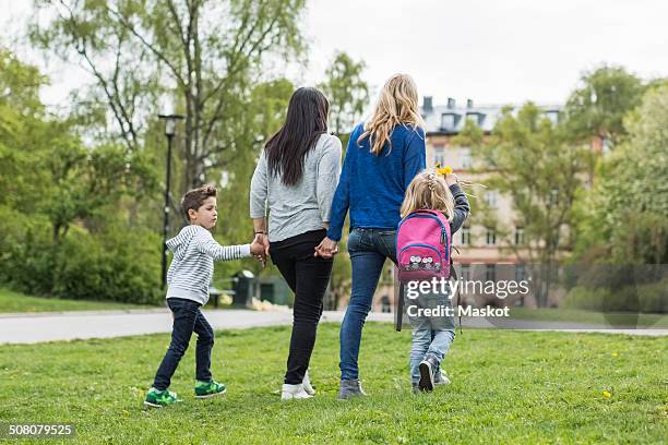 rear view of female homosexual family walking in park - lesbian mom stock pictures, royalty-free photos & images