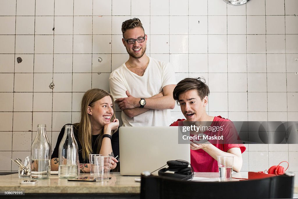 Young business people discussing over laptop in creative office
