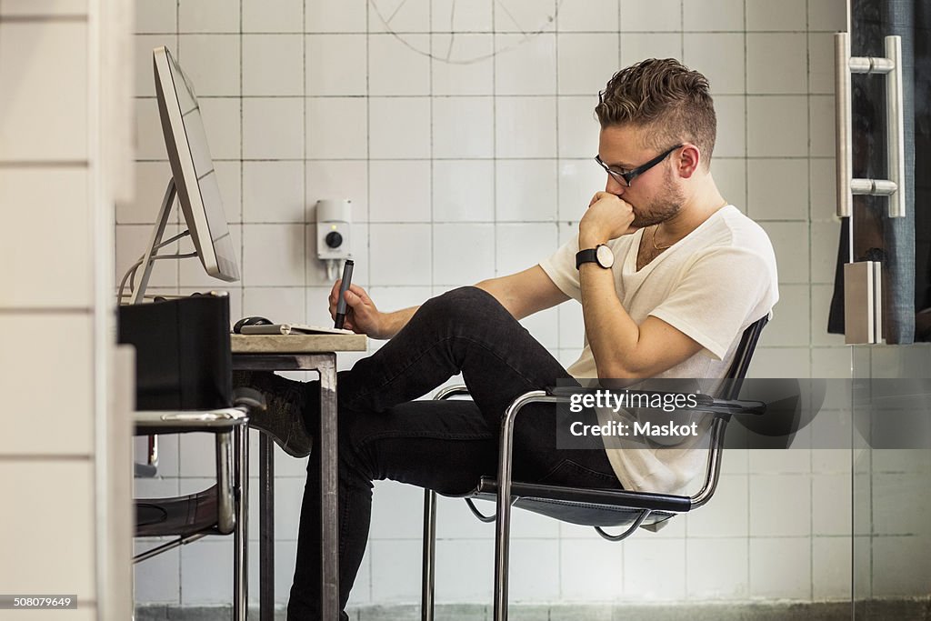 Side view of young businessman at computer desk in new office