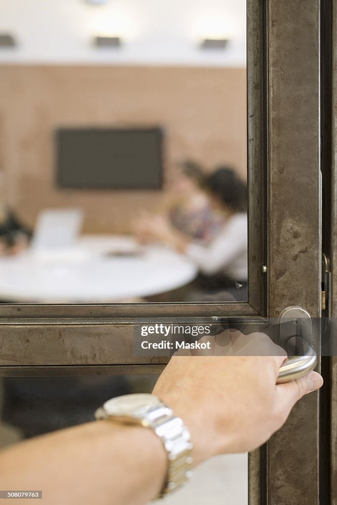 Businesswoman's hand opening door handle in creative office