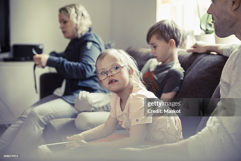 Portrait of handicapped girl sitting with family on sofa at home