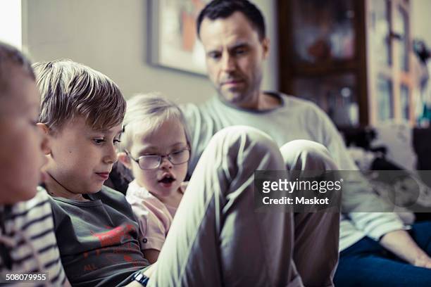 Siblings sitting with father in house