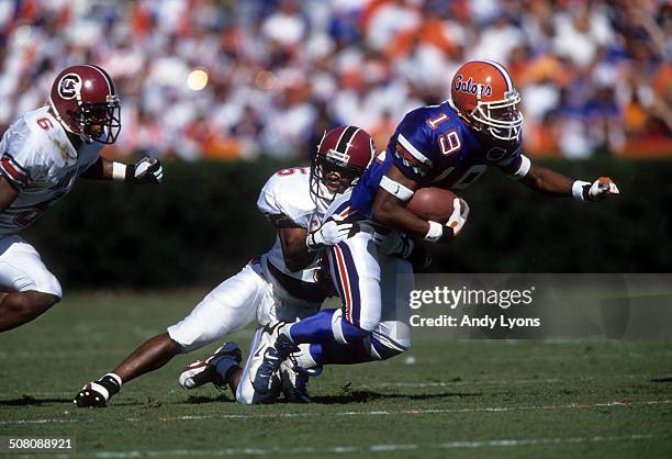 Ike Hilliard of the Florida Gators is tackled by Terry Cousin of the South Carolina Gamecocks on November 16, 1996 at Ben Hill Griffin Stadium in...