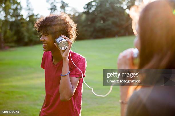 young multi-ethnic couple communicate with a tin can phone - plåtburkstelefon bildbanksfoton och bilder