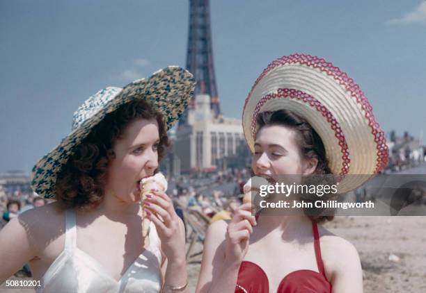 Two girls enjoy ice creams on the sands at Blackpool, July 1954. Blackpool Tower can be seen in the background. Original publication: Picture Post -...