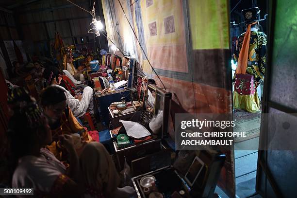 This picture taken on January 19, 2016 shows Chinese opera artists backstage and on stage during a performance held in a village in Nakhon Pathom...