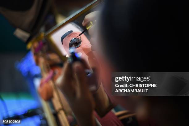 This picture taken on January 19, 2016 shows a Chinese opera artist applying make-up backstage ahead of a performance held in a village in Nakhon...