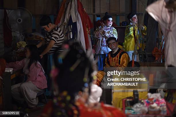 This picture taken on January 19, 2016 shows dressed-up Chinese opera artists waiting to take to the stage during a performance held in a village in...