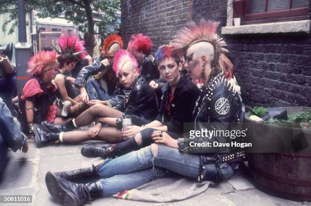 Group of punks colonise a street corner with a can of beer, 1983.