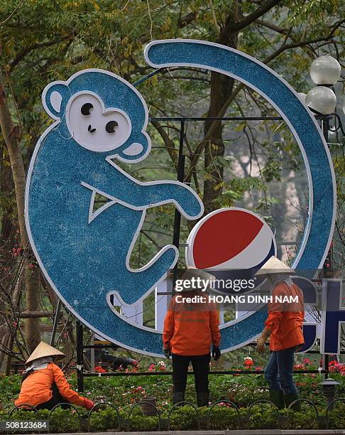 Municipal workers arrange flowers next to a decoration bearing the image of a monkey in downtown Hanoi on February 3, 2016 as Vietnamese prepare to...