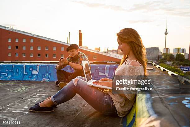 young adults sitting on a roof, back lit - berlin summer stockfoto's en -beelden