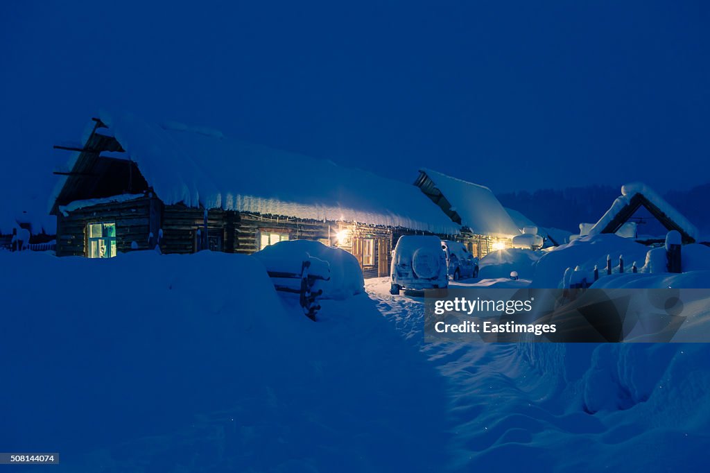 Lightened wooden house in a world of ice and snow at night/Xinjiang,China.