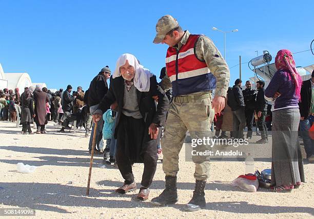 Turkish soldier helps an elderly man walk towards a registration center before being placed at a tent city in Suruc district of Turkey's Sanliurfa...