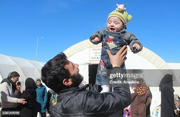 Man holds up a baby as he wait for registration before being placed at a tent city in Suruc district of Turkey's Sanliurfa province on Frebruary 3...