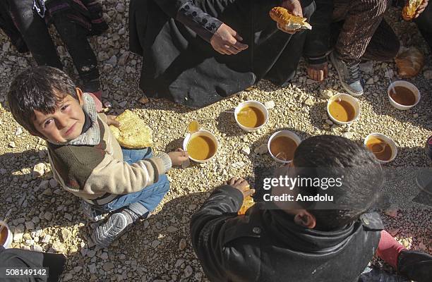 Children eat their meals as they wait for registration before being placed at a tent city in Suruc district of Turkey's Sanliurfa province on...