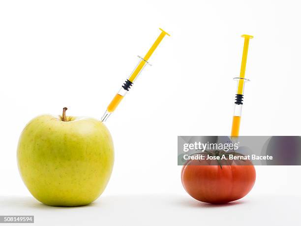 yellow apple and tomato with a syringe stuck concept of transgenic foods - surgical pin stock pictures, royalty-free photos & images