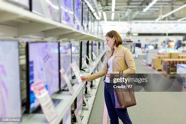 woman chooses a tv in the store - huishoudelijke apparatuur stockfoto's en -beelden