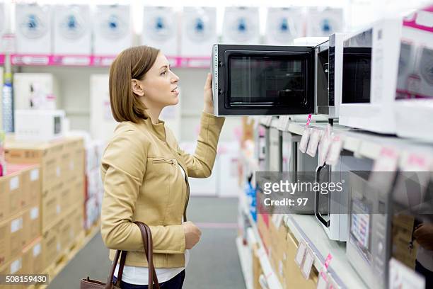 woman buys the microwave - microwave stock pictures, royalty-free photos & images