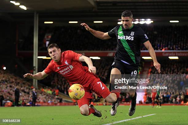James Milner of Liverpool goes down under a challenge from Jonathan Walters of Stoke during the Capital One Cup Semi-Final Second Leg match between...