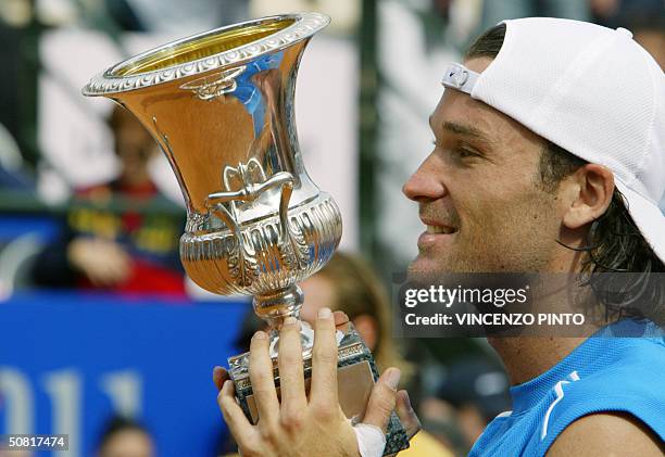 Spanish sixth seed Carlos Moya smiles as he receives the cup after winning the final of the 2.4 million-euro Italian Masters against Argentine fifth...