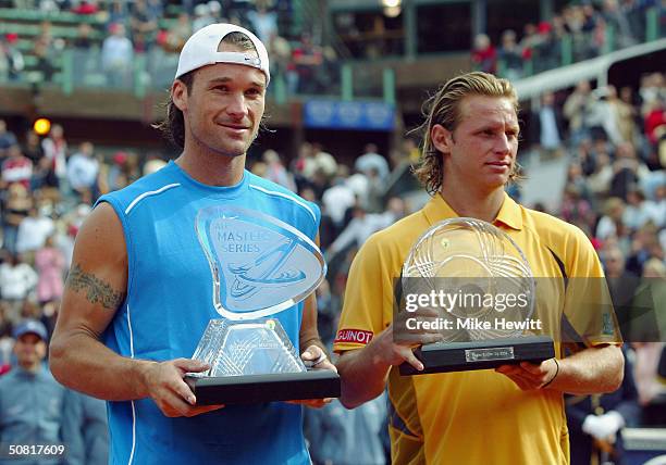 Carlos Moya of Spain and David Nalbandian of Argentina hold up the winner's and runners-up trophies respectively in the Telecom Italia Tennis Masters...