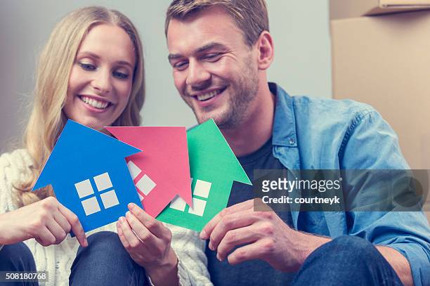 couple with 3 house symbols. choice concept. - search new home stock pictures, royalty-free photos & images
