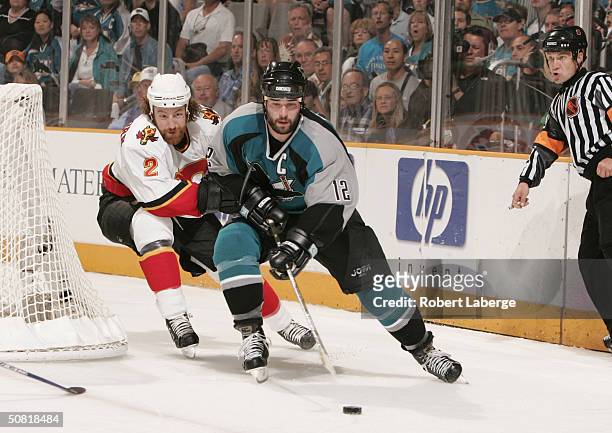 Patrick Marleau of the San Jose Sharks skates with the puck under pressure from Mike Commodore of the Calgary Flames during Game one of the 2004 NHL...