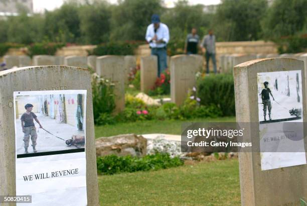 Photographs depicting the abuse of an Iraqi prisoner in Abu Ghraib prison are seen attached to gravestones at the Commonwealth military cemetery May...