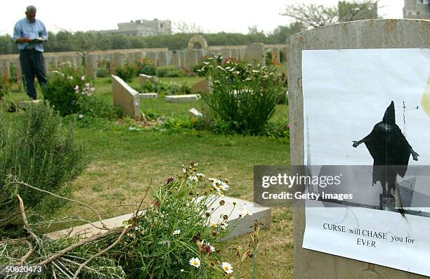 Photograph depicting the abuse of an Iraqi prisoner in Abu Ghraib prison is seen attached to a gravestone at the Commonwealth military cemetery May...