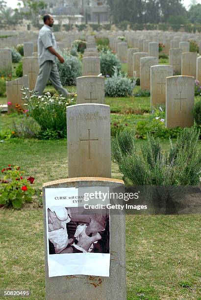 Photograph depicting the abuse of an Iraqi prisoner in Abu Ghraib prison is seen attached to a headstone at the Commonwealth military cemetery May...
