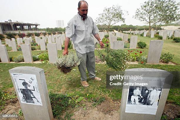 Photographs depicting the abuse of an Iraqi prisoner in Abu Ghraib prison are seen attached to headstones at the Commonwealth military cemetery May...