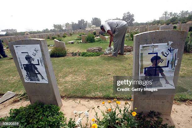 Photographs depicting the abuse of an Iraqi prisoner in Abu Ghraib prison are seen attached to headstones at the Commonwealth military cemetery May...