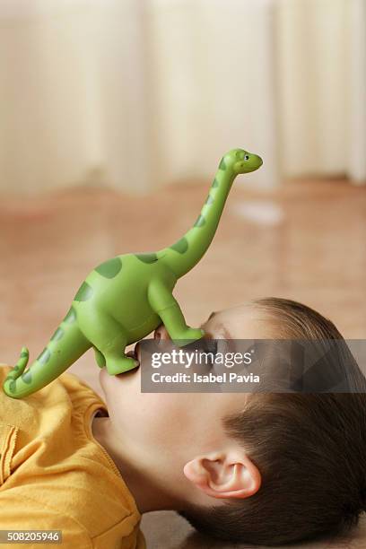 boy with dinosaur on his face - toy animal stock-fotos und bilder