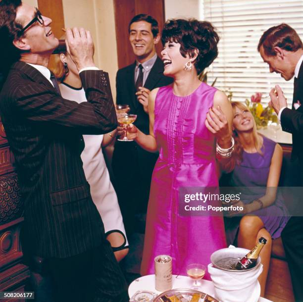 Sixties Fashion - Model Jean Rollins wears a pink sleeveless satin party dress at a drinks reception circa 1965.