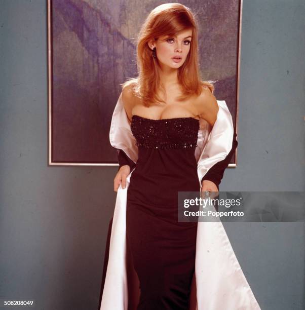 English model and actress Jean Shrimpton posed wearing a white lined long black jacket over a black strap-less evening dress in 1965.