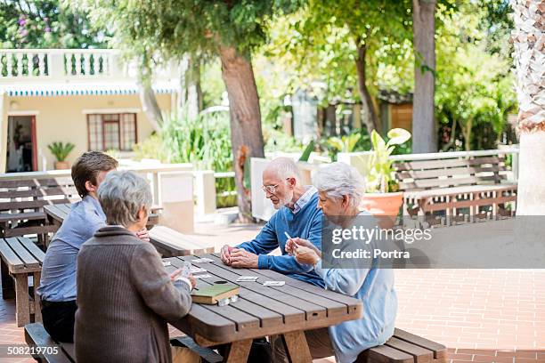 caretaker playing cards with senior people - urbanización para jubilados fotografías e imágenes de stock