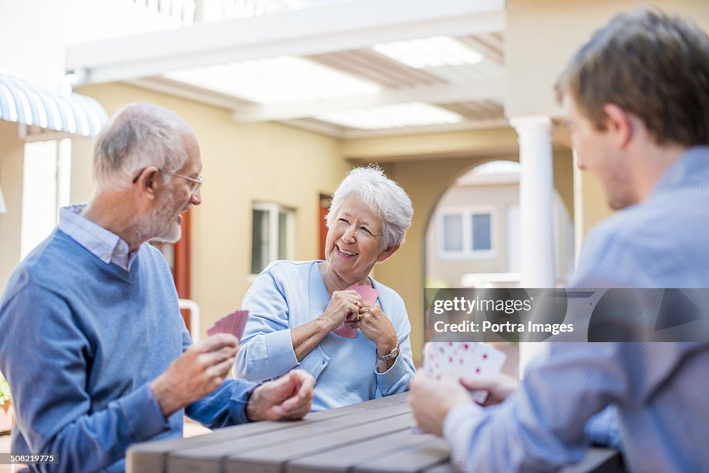 Senior people playing cards with male caretaker