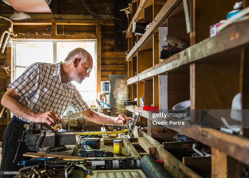 Confident senior carpenter sitting in workshop