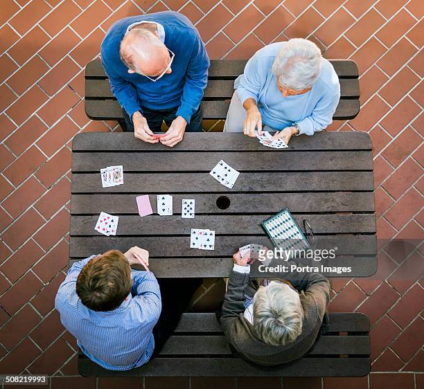 senior people and caretaker playing cards at table - senior men playing cards stock pictures, royalty-free photos & images