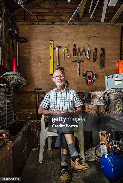 Confident senior carpenter sitting in workshop