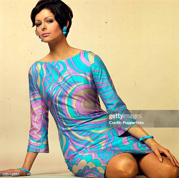 Sixties Fashion - A young female model wears a Pucci style blue and pink patterned mini dress with matching earings circa 1966.