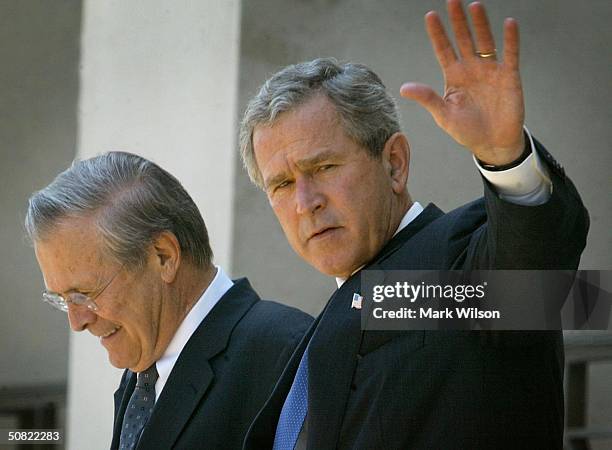 President George W. Bush waves as he and Secretary of Defense Donald Rumsfeld walk outside of the Pentagon after a classified briefing May 10, 2004...