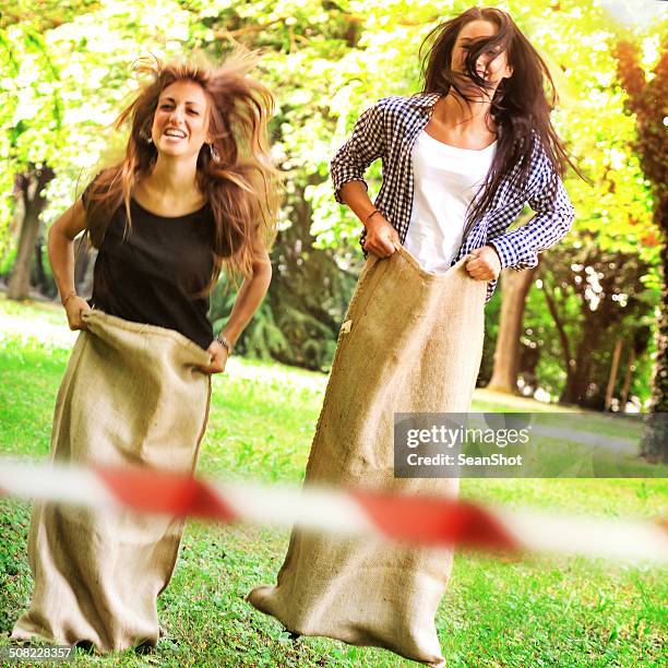 two young woman playing at sack race - sack race stock pictures, royalty-free photos & images