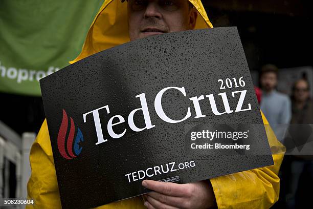 Supporter of Senator Ted Cruz, a Republican from Texas and 2016 presidential candidate, stands in the rain as while holding a sign before Senator Ted...