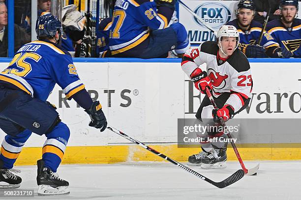 Bobby Farnham of the New Jersey Devils handles the puck as Chris Butler of the St. Louis Blues defends on January 12, 2016 at Scottrade Center in St....