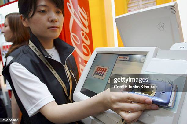 Woman demonstrates how to buy products at a convenience store paying with your phone rather than a ticket during a business show on May 11, 2004 in...